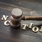 Gavel,and,word,sanctions,spelled,in,letters,on,table
