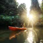 Cheerful woman sea kayaking among karst formations and mangrove forest on Krabi